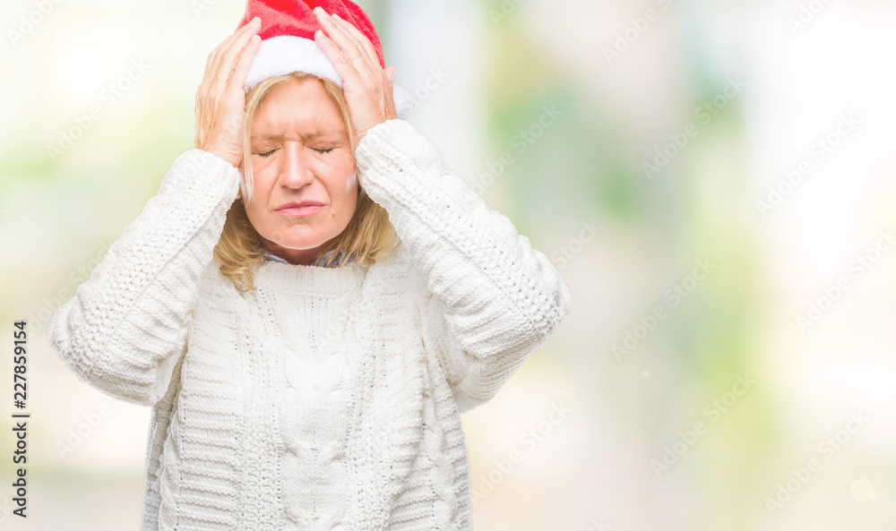 Middle age blonde woman wearing christmas hat over isolated background suffering from headache desperate and stressed because pain and migraine. Hands on head.