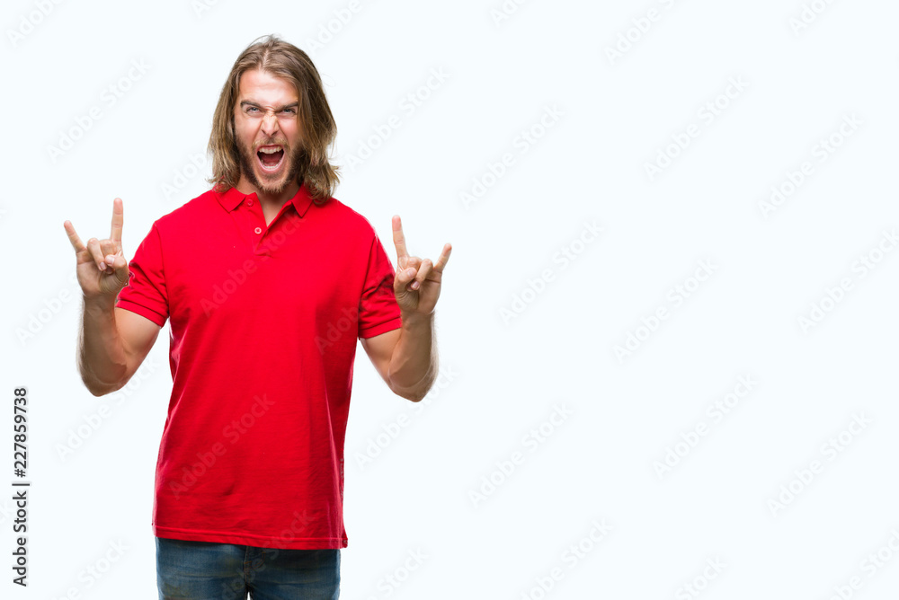 Young handsome man with long hair over isolated background shouting with crazy expression doing rock symbol with hands up. Music star. Heavy concept.
