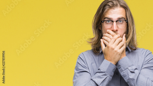Young handsome business man with long hair over isolated background shocked covering mouth with hands for mistake. Secret concept.