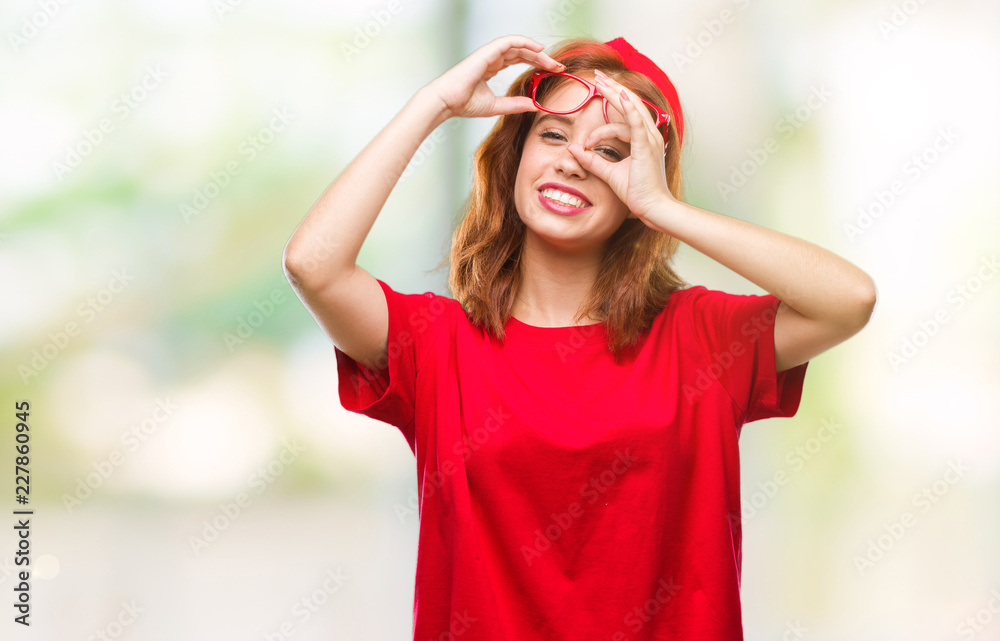Young beautiful woman over isolated background doing ok gesture with hand smiling, eye looking through fingers with happy face. Young beautiful woman over isolated background doing ok gesture with hand smiling, eye looking through fingers with happy face.