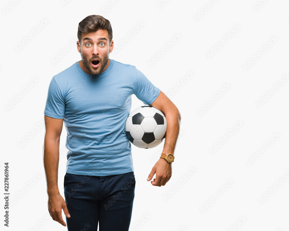 Young handsome man holding soccer football ball over isolated background scared in shock with a surprise face, afraid and excited with fear expression Young handsome man holding soccer football ball over isolated background scared in shock with a surprise face, afraid and excited with fear expression