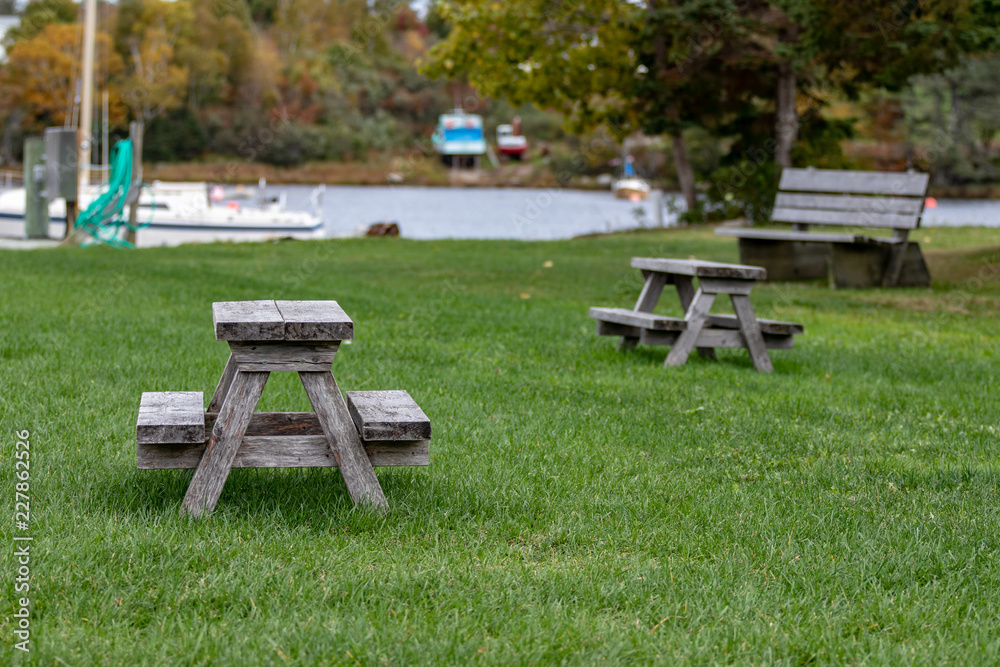 Benches and picinic tables at marina, blurred boat, blurred water in background.