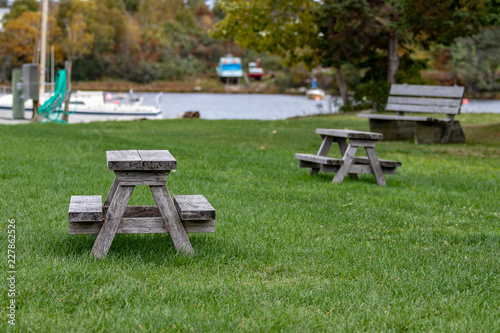 Benches and picinic tables at marina, blurred boat, blurred water in background.