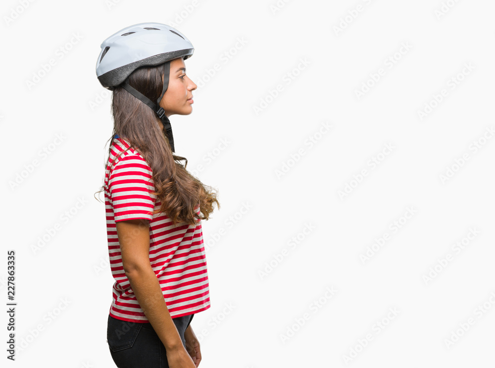 Young arab cyclist woman wearing safety helmet over isolated background looking to side, relax profile pose with natural face with confident smile. Young arab cyclist woman wearing safety helmet over isolated background looking to side, relax profile pose with natural face with confident smile.