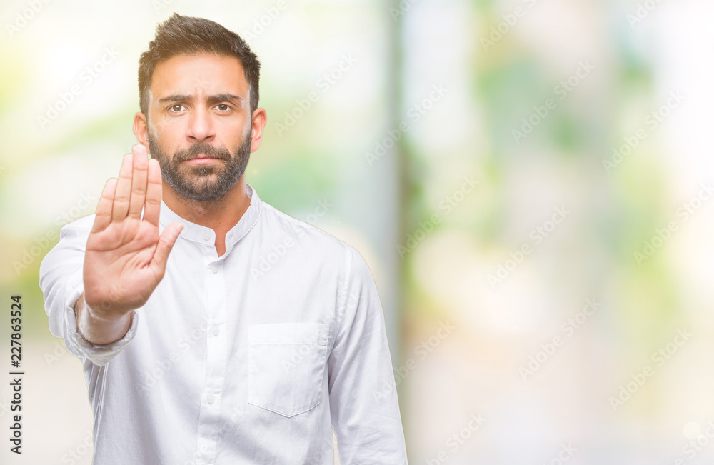 Adult hispanic man over isolated background doing stop sing with palm of the hand. Warning expression with negative and serious gesture on the face.