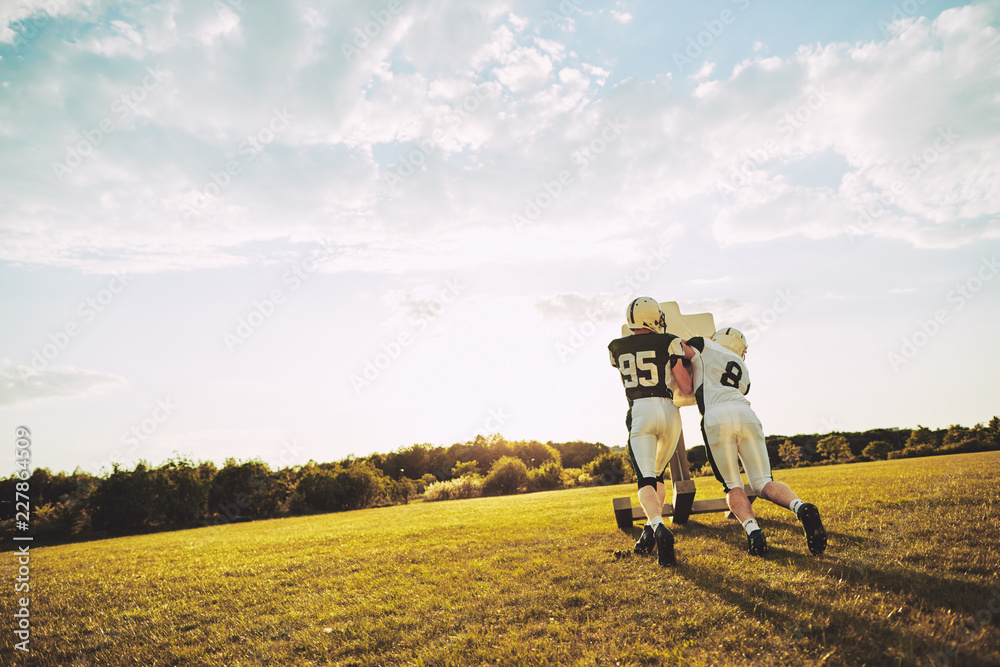 © Flamingo Images - American football players doing sled tackle drills together duri © Flamingo Images - American football players doing sled tackle drills together duri