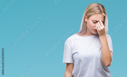 Young blonde woman over isolated background tired rubbing nose and eyes feeling fatigue and headache. Stress and frustration concept.