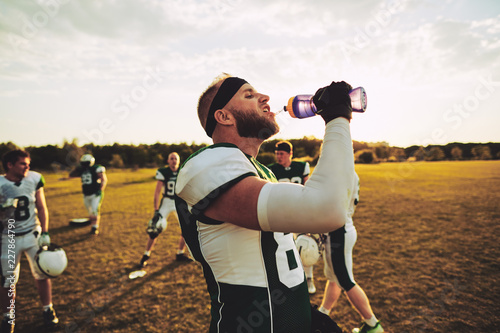 American football player drinking water during practice outside photo