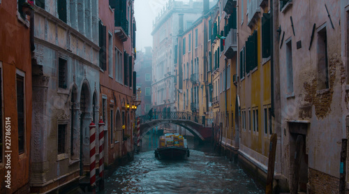 Single boat cruising on a canal in Venice Italy, winter foggy morning © chronisyan