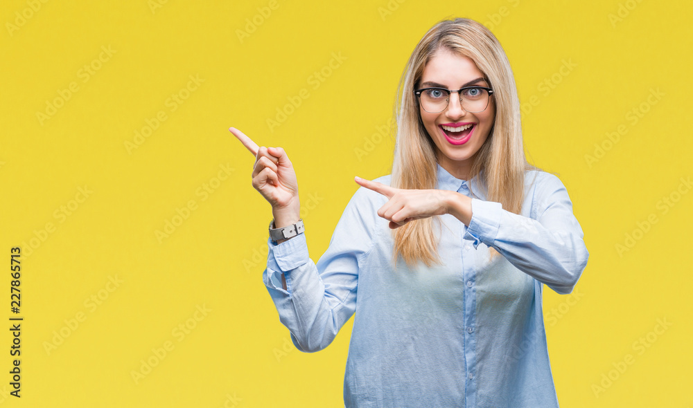 Young beautiful blonde business woman wearing glasses over isolated background smiling and looking at the camera pointing with two hands and fingers to the side. Young beautiful blonde business woman wearing glasses over isolated background smiling and looking at the camera pointing with two hands and fingers to the side.