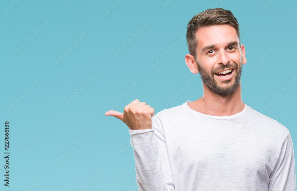 Young handsome man over isolated background smiling with happy face looking and pointing to the side with thumb up. Young handsome man over isolated background smiling with happy face looking and pointing to the side with thumb up.