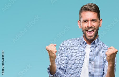 Konstfotografi Young handsome man wearing white t-shirt over isolated background very happy and excited doing winner gesture with arms raised, smiling and screaming for success