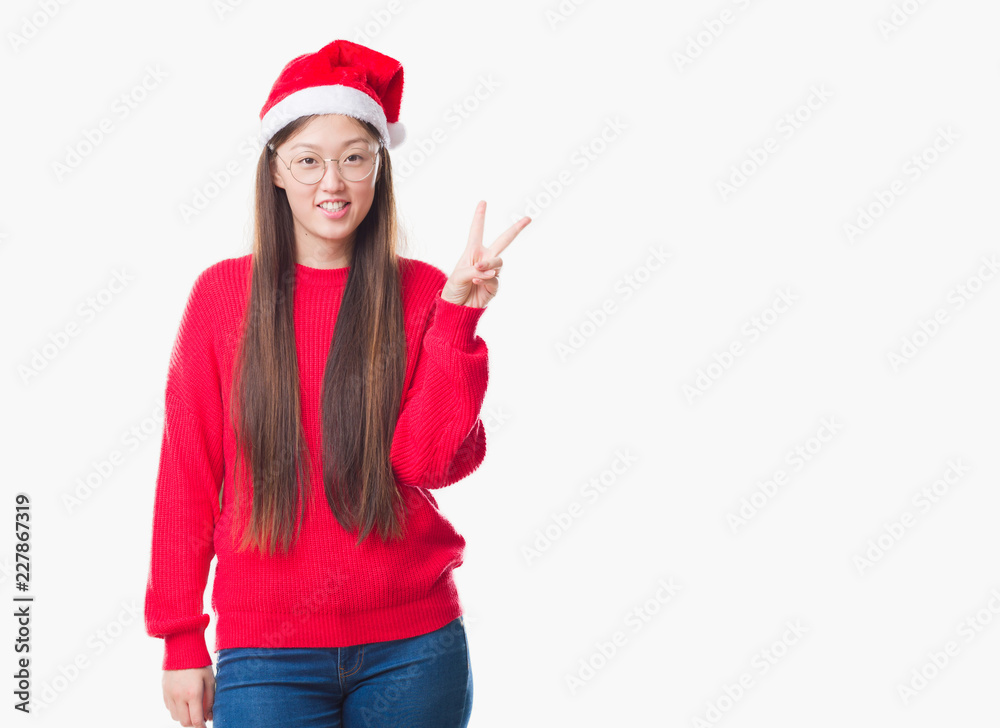 Young Chinese woman over isolated background wearing christmas hat showing and pointing up with fingers number two while smiling confident and happy. Young Chinese woman over isolated background wearing christmas hat showing and pointing up with fingers number two while smiling confident and happy.
