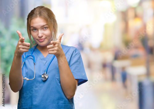 Young caucasian doctor woman wearing surgeon uniform over isolated background pointing fingers to camera with happy and funny face. Good energy and vibes.