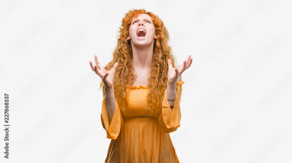 Young redhead woman crazy and mad shouting and yelling with aggressive expression and arms raised. Frustration concept.