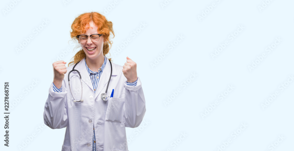 Young redhead woman wearing doctor uniform excited for success with arms raised celebrating victory smiling. Winner concept. Young redhead woman wearing doctor uniform excited for success with arms raised celebrating victory smiling. Winner concept.