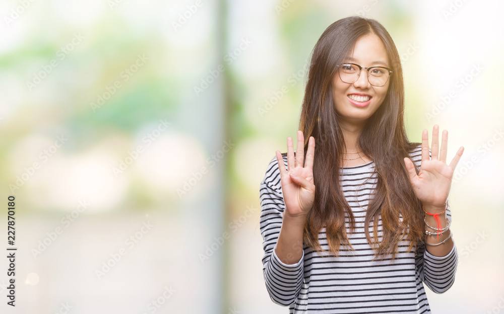 Young asian woman wearing glasses over isolated background showing and pointing up with fingers number nine while smiling confident and happy.