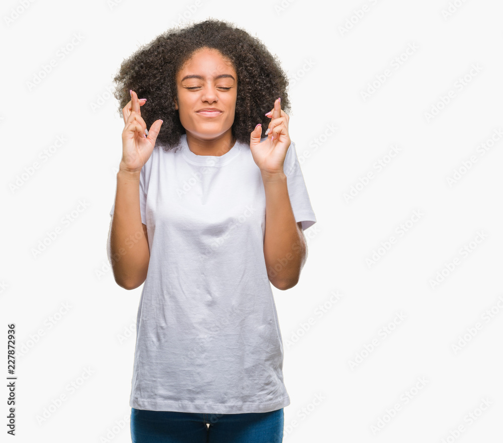 Young afro american woman over isolated background smiling crossing fingers with hope and eyes closed. Luck and superstitious concept. Young afro american woman over isolated background smiling crossing fingers with hope and eyes closed. Luck and superstitious concept.