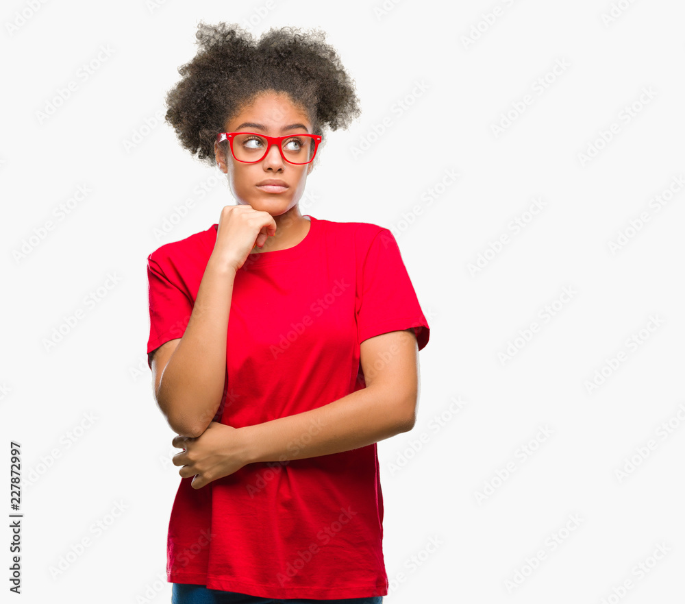Young afro american woman wearing glasses over isolated background with hand on chin thinking about question, pensive expression. Smiling with thoughtful face. Doubt concept. Young afro american woman wearing glasses over isolated background with hand on chin thinking about question, pensive expression. Smiling with thoughtful face. Doubt concept.