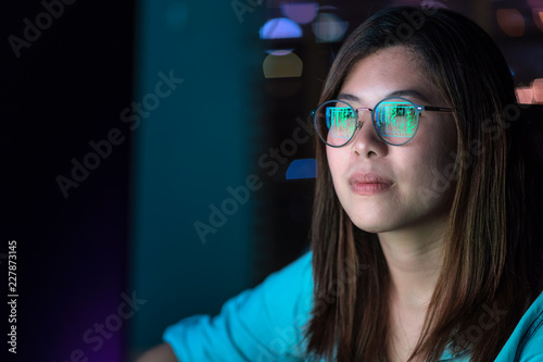 Obraz na płótnie Closeup Asian Businesswoman working hard and looking the digital graphic on the table with front of computer desktop in workplace at late with serious action, Work hard and too late concept w salonie