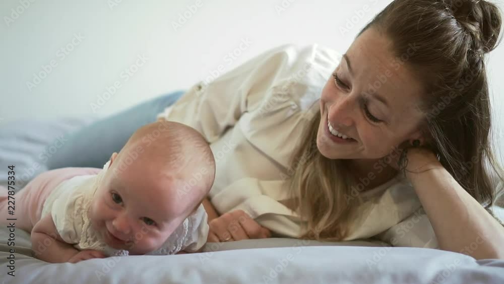 A Portrait of a beautiful mother with her 2 month old baby in the bedroom A Portrait of a beautiful mother with her 2 month old baby in the bedroom