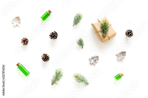 New Year pattern with pine sprigs, cones, spruce figure, fir oil and new year gift decorated with craft paper and pine sprout on white background top view