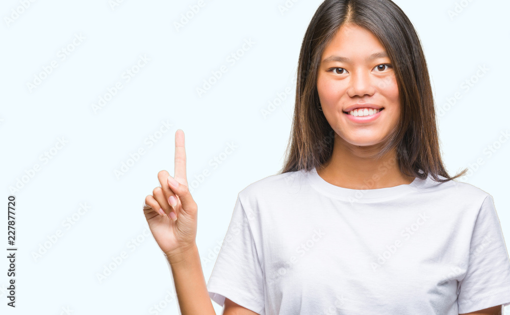 Young asian woman over isolated background showing and pointing up with finger number one while smiling confident and happy. Young asian woman over isolated background showing and pointing up with finger number one while smiling confident and happy.