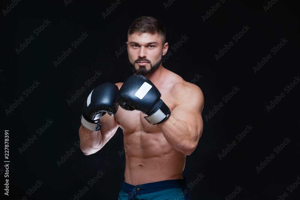 Strong muscular boxer in black boxing gloves. Isolated on black background. Strong muscular boxer in black boxing gloves. Isolated on black background.
