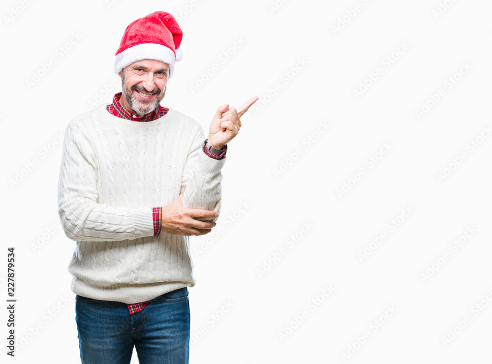 Middle age hoary senior man wearing christmas hat over isolated background with a big smile on face, pointing with hand and finger to the side looking at the camera.