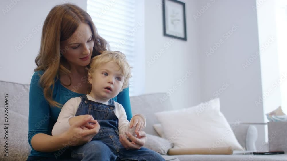 Young mother relaxing at home with her son and watching television together Young mother relaxing at home with her son and watching television together