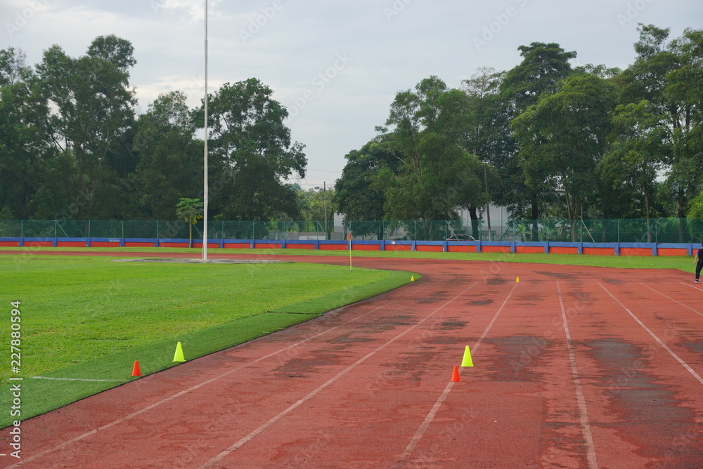 Fototapeta premium track and fields with 2 yellow cone on track with artificial grass inside a stadium