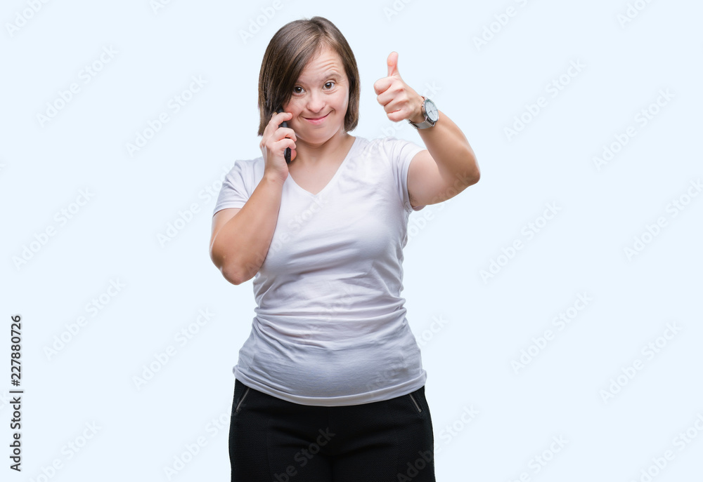 Young adult woman with down syndrome taking using smartphone over isolated background happy with big smile doing ok sign, thumb up with fingers, excellent sign Young adult woman with down syndrome taking using smartphone over isolated background happy with big smile doing ok sign, thumb up with fingers, excellent sign