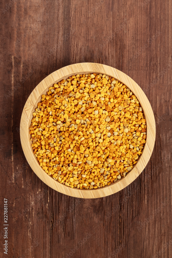 Healthy organic food. Bee pollen, shot from above in a wooden bowl on a dark rustic background with a place for text Healthy organic food. Bee pollen, shot from above in a wooden bowl on a dark rustic background with a place for text