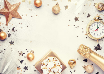 Christmas or New Year composition, frame, pink background with gold Christmas decorations, stars, snowflakes, balls, alarm clock, gift box and bottle of champagne, top view