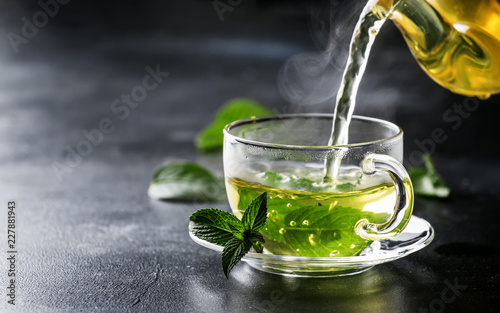 Fotografie, Obraz Hot chinese green tea with mint, with splash pouring from the kettle into the cu