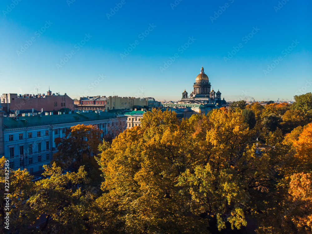 Autumn urban landscape. Blue Sunny sky and yellow tree crowns. Dome of St. Isaac Cathedral. Saint-Petersburg.
