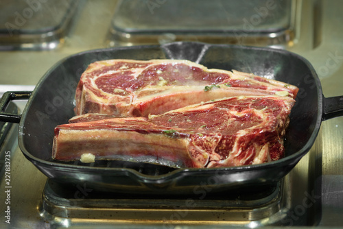 Raw fresh meat T-bone steak on grill iron pan