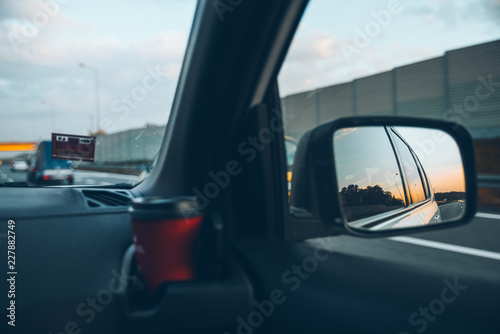 sunset reflection in car mirror on highway