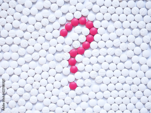 Fotografía Question mark formed by unique pink pills among white ones background