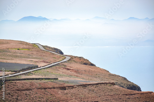 Voulcanic scenic landscape on Lanzarote island and narrow asphalt road along ocean shore and rocks, Canary islands, Spain