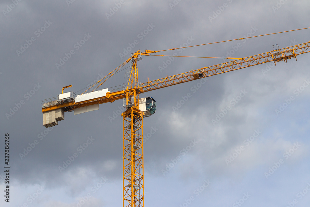 Yellow tower crane on the background of rain clouds Yellow tower crane on the background of rain clouds