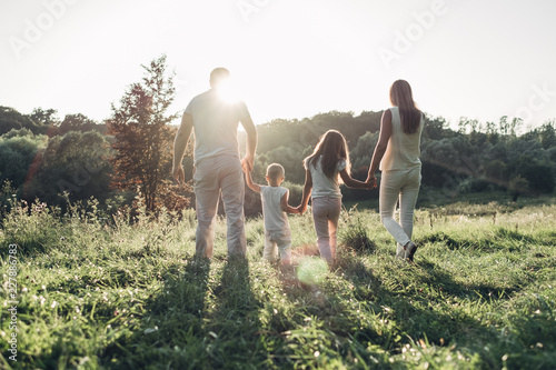 Adult couple with their little children having picnic in the Park Outside the City, Family Weekend Concept, Four People Enjoying Summer Time