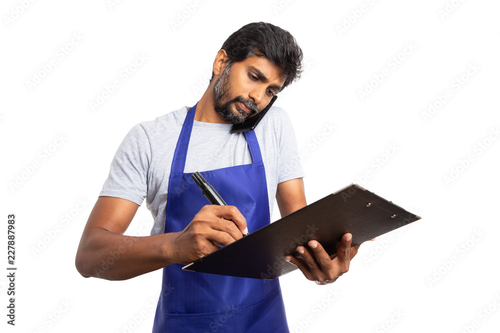 Hypermarket employee talking on the phone and checking clipboard.