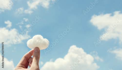 Woman hand holding cotton wool on cloud sky background. The development of the imagination, copy space. photo