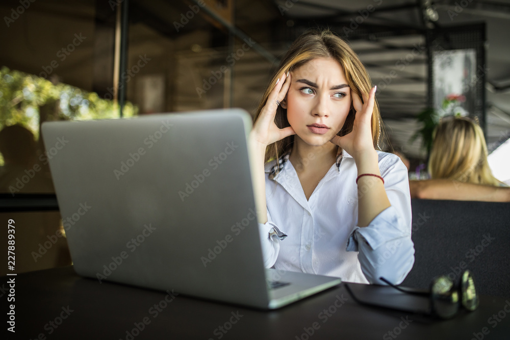 Stressed female student having headache touching temples preparing for test in cafe. Frustrated millennial girl feels nervous or tired, afraid of exam failure, suffering from anxiety or panic attack