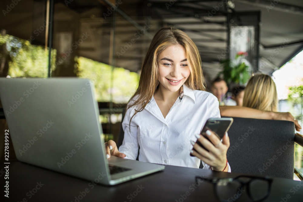 Smile woman holds phone, uses laptop computer for online communication at terrace cafe Smile woman holds phone, uses laptop computer for online communication at terrace cafe