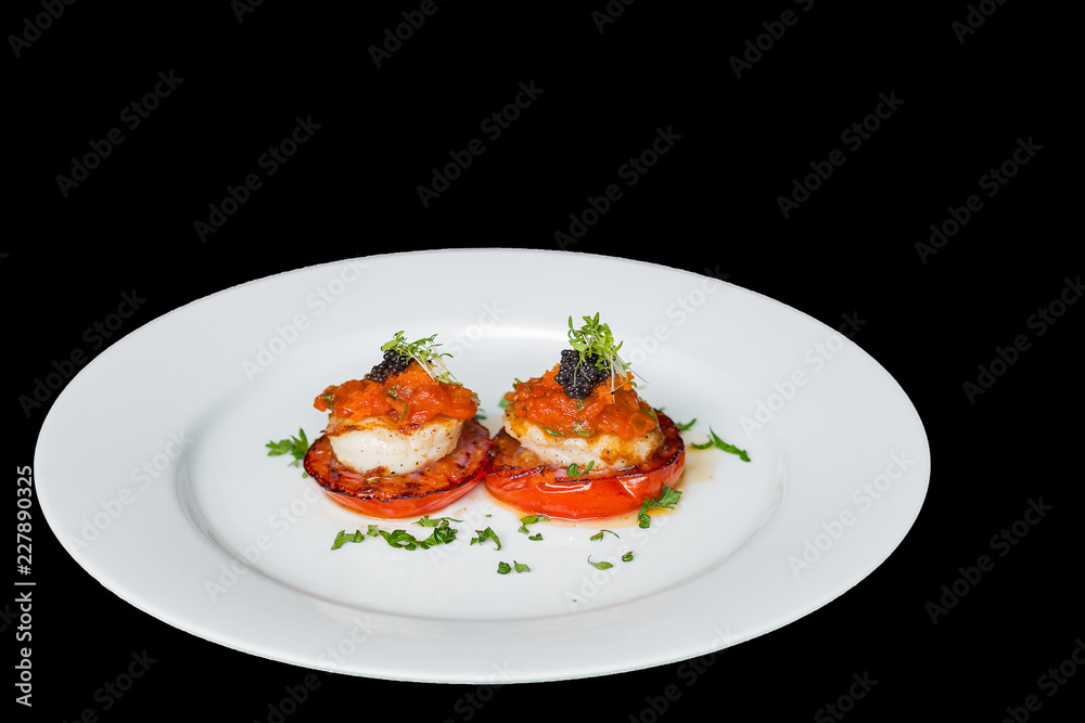 Scallops, tomatoes and ketchup on white plate, black background Scallops, tomatoes and ketchup on white plate, black background