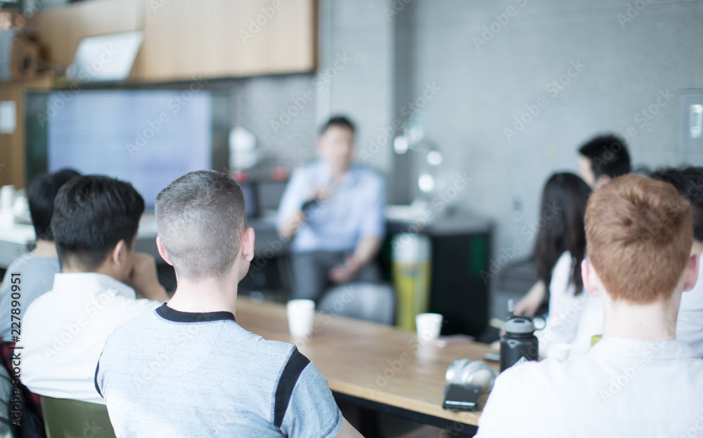 Obraz premium Group Meeting with Diverse People Listening to Speaker. Group Discussion. Tech Executive Manager Speaker Having Business Meeting with Young Business People. Presenter and Young Men and Women Audience.
