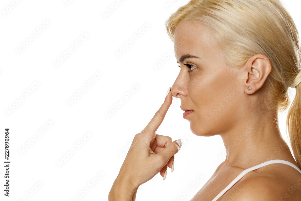 portrait of young blonde woman with long hair touching her nose on white background portrait of young blonde woman with long hair touching her nose on white background