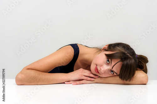 Studio photo portrait of a beautiful brunette girl on a white background sitting at the table.